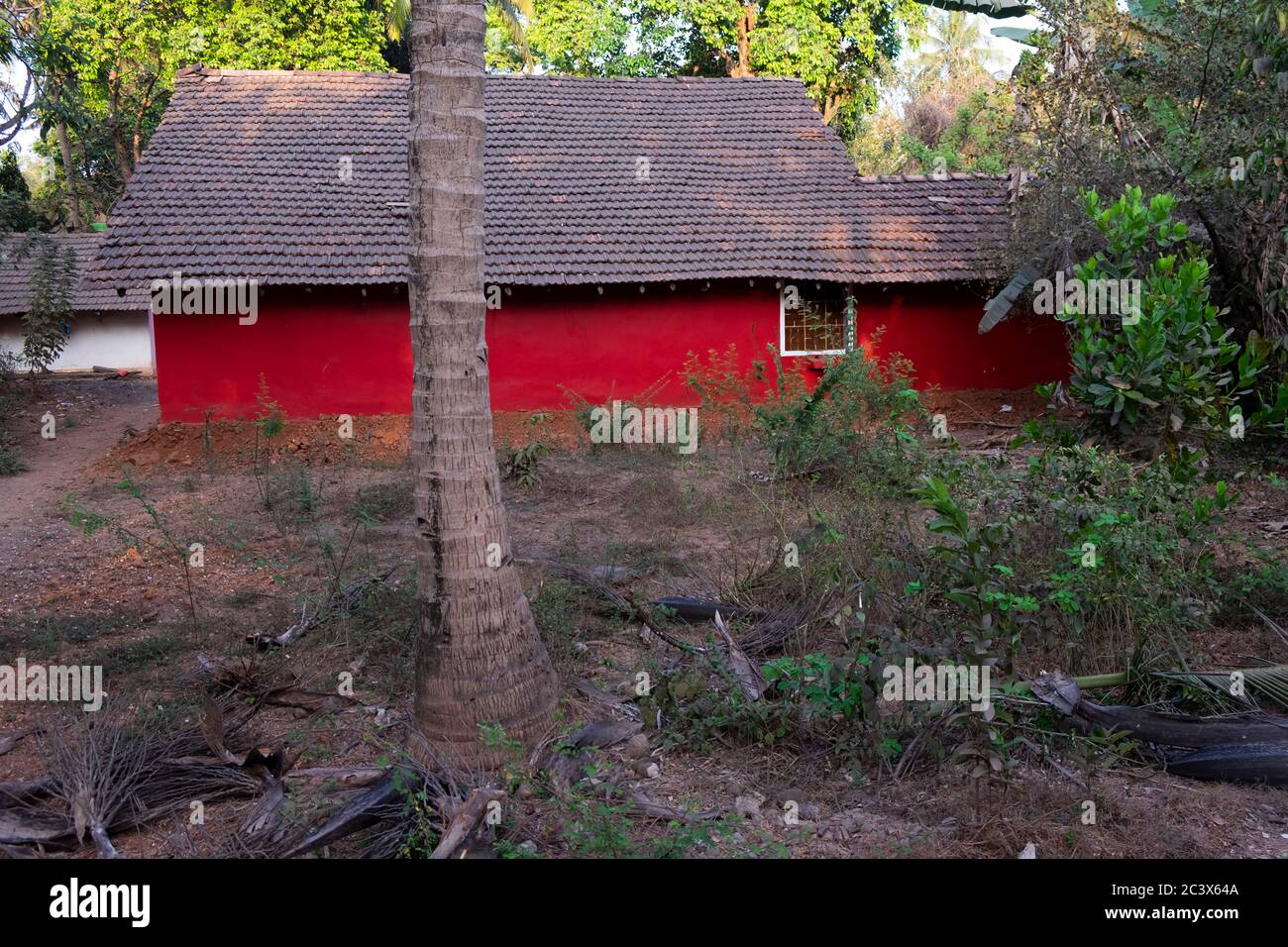 Ein Haus in hellroter Farbe in einem Dorf in Goa, Indien. Stockfoto