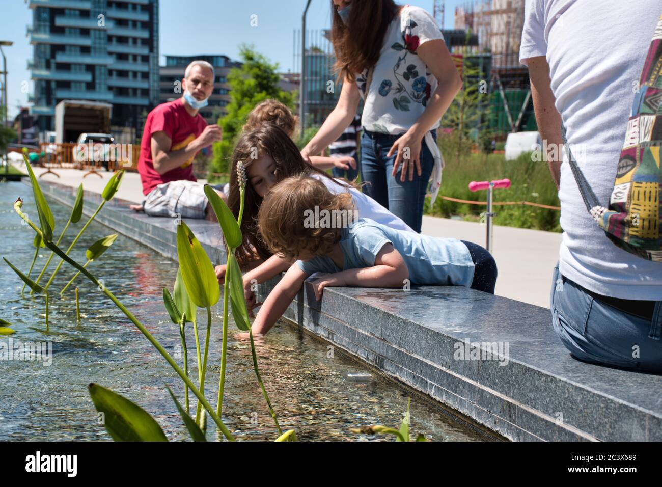 Mailand, Italien 06.20.2020: Kinder genießen die Sonne und spielen mit dem Wasser im neuen Park der Baumbibliothek in Mailand Stockfoto