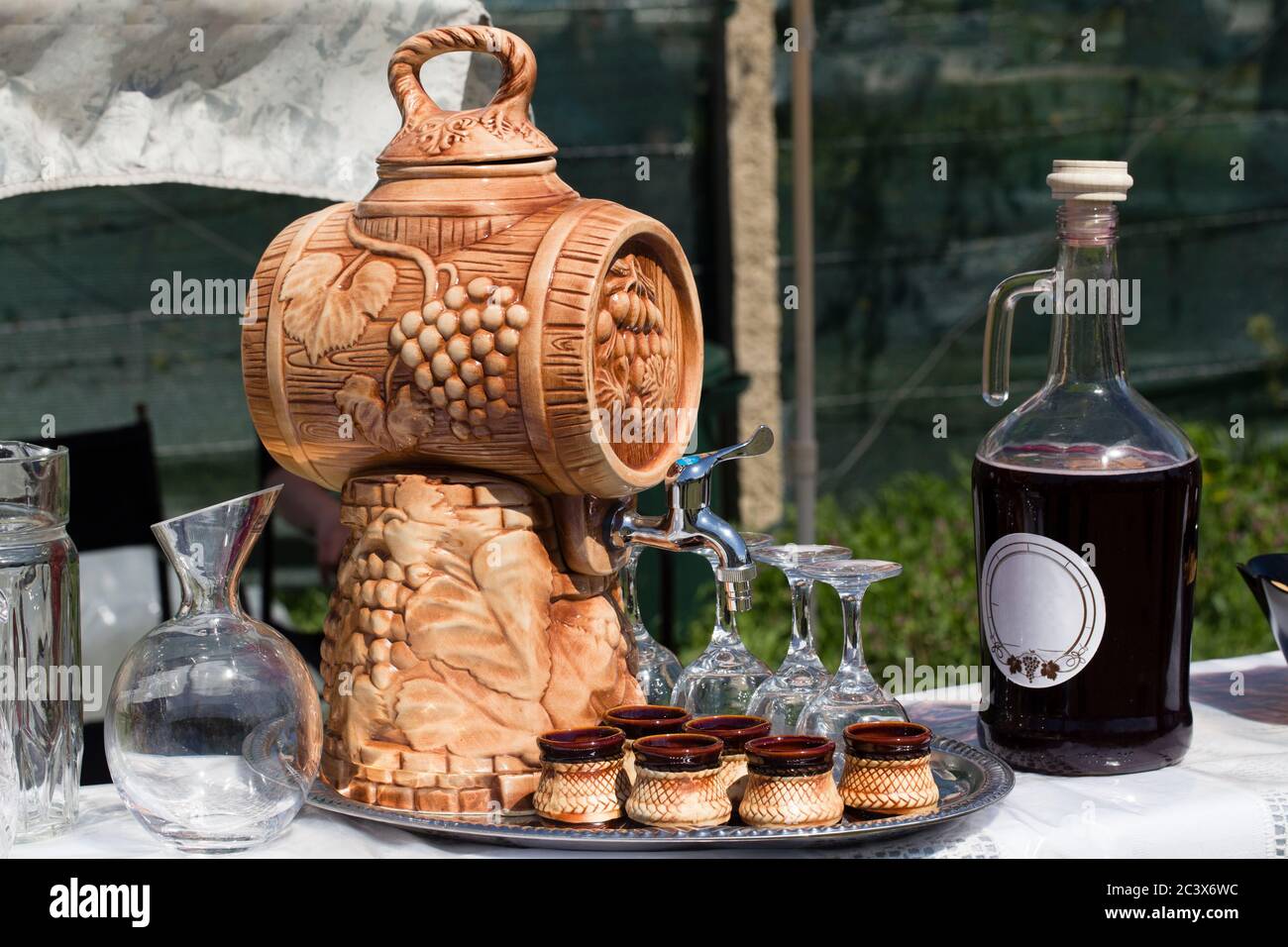 Traditionelles Fass mit Saft. Flasche und Tassen für frischen Saft stehen daneben. Stockfoto