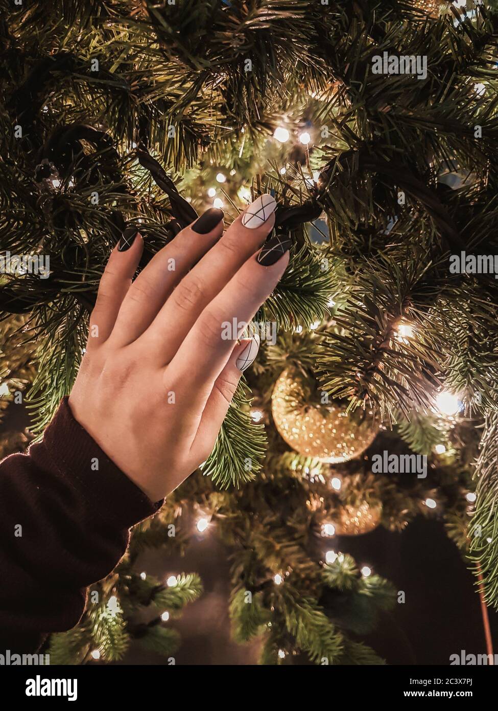 Frau Hand mit schönen schwarz-weißen Maniküre berühren Weihnachtsbaum mit Vorfreude auf Silvester Feier. Festliche fröhliche Stimmung. Ansicht schließen Stockfoto