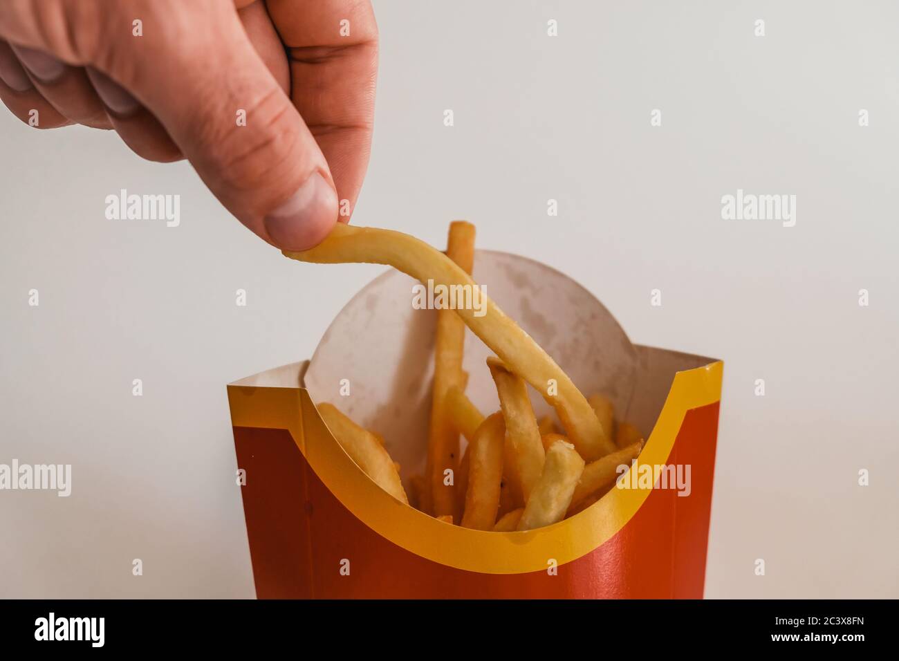 Lviv / Ukraine - April 2020: Nahaufnahme der Hand eines hungrigen Mannes, der ein Stück pommes aus der McDonalds-Tasche nimmt. Bestellung ungesunde Essen zum Mitnehmen Stockfoto