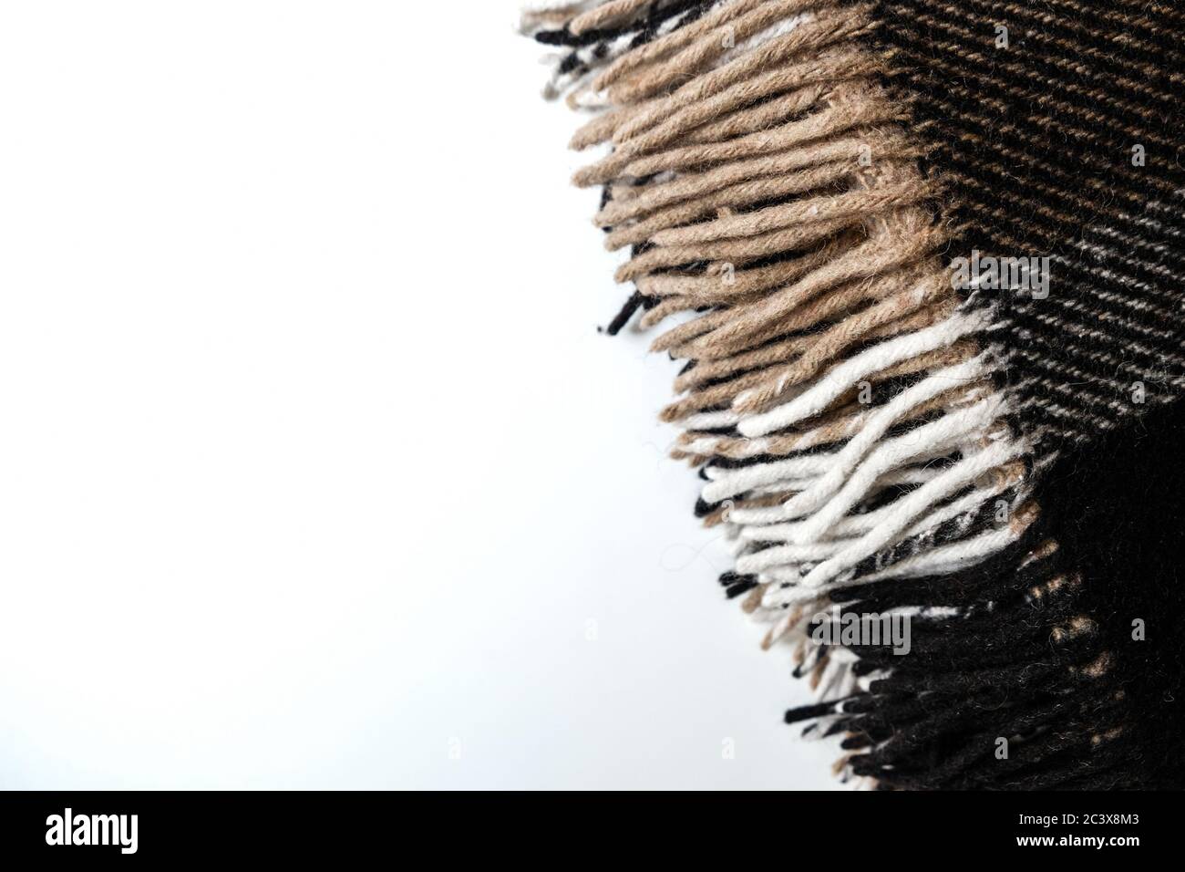 Braune Karaid Decke mit langen Kanten. Nahaufnahme auf einer weißen Fläche. Textil im Interior Design. Wärmendes, gemütliches Material zum Verdecken beim Lernen Stockfoto