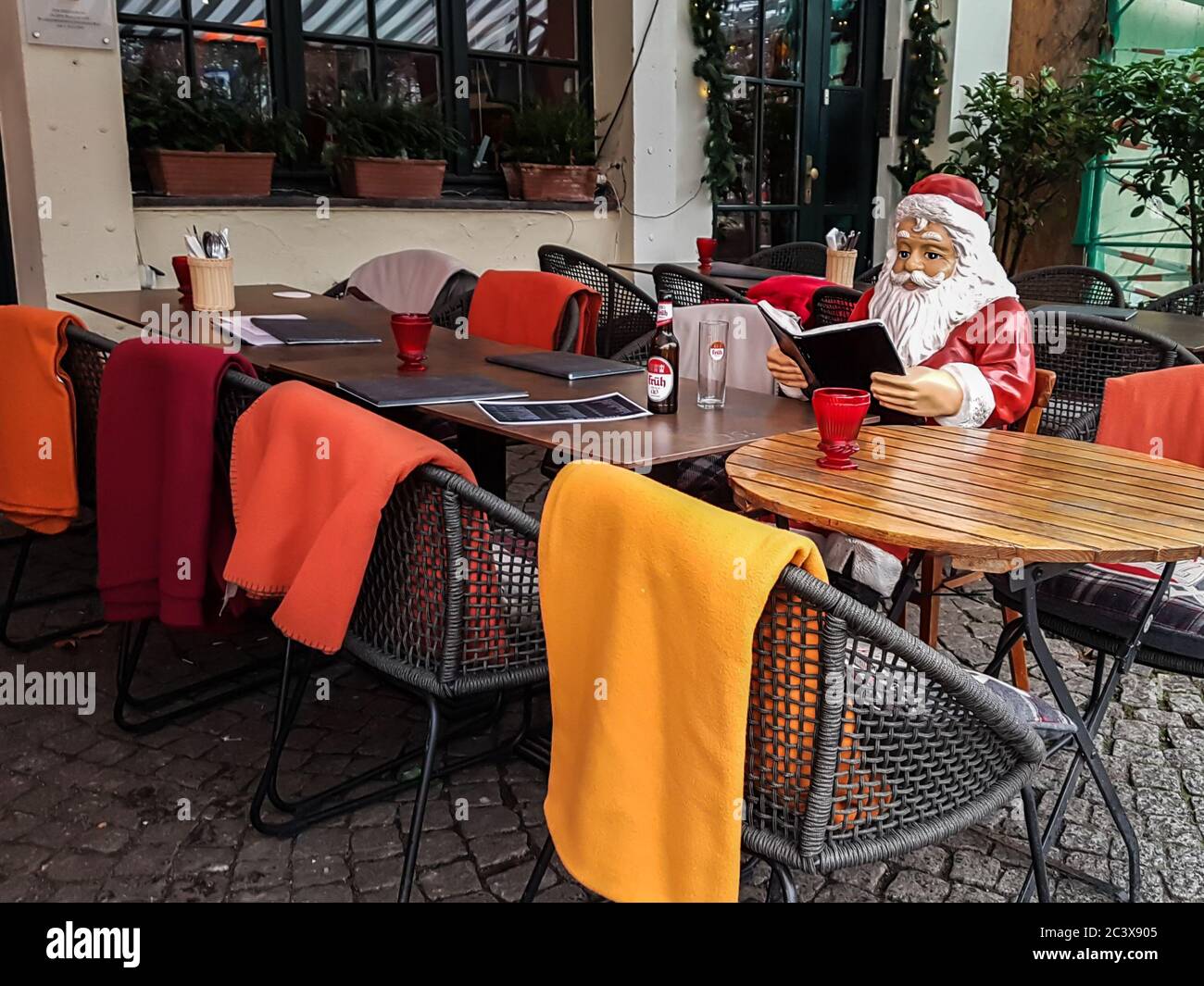 Köln / Deutschland - 2018: Weihnachtsmann liest das Menü auf einer Terrasse vor einem Café am Fluss in Köln. Festliche Feiertagsstimmung. Warme und gemütliche Farbe Stockfoto