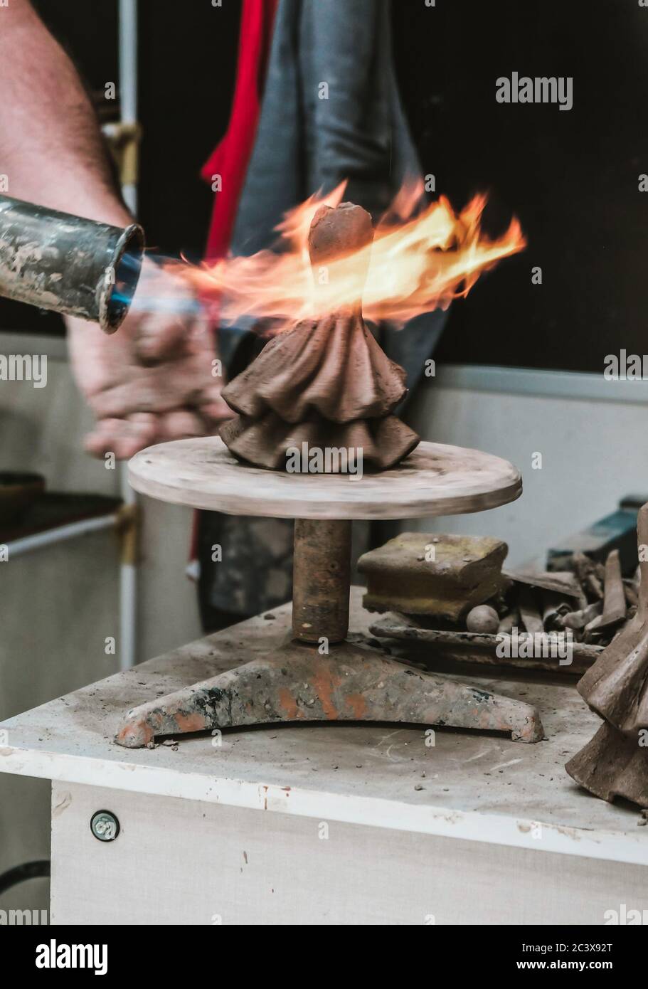 Cordoba / Spanien - 2019: Heimischer Handwerker, der irdne Keramikfigur mit offener Flamme im Souvenirladen verbrennt. Statue in einem Geschäft machen. Lehmziegen Stockfoto
