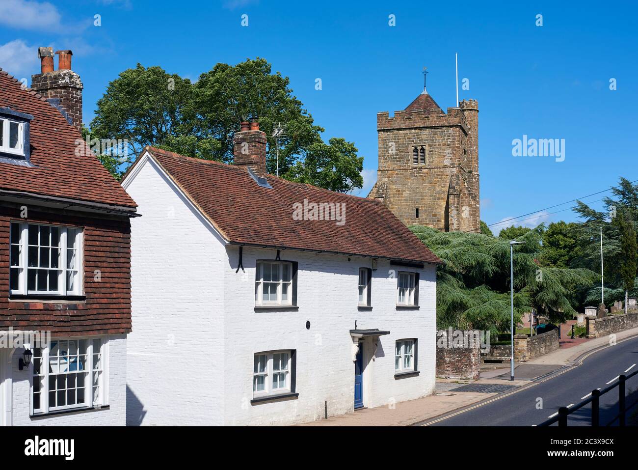Die High Street in Battle, East Sussex, Südengland, mit Hütten und dem historischen St. Mary's Kirchturm Stockfoto