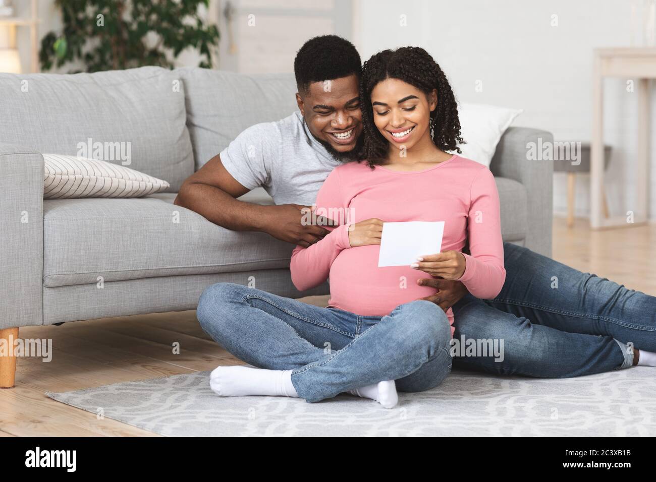Schwangere Paar auf dem Boden sitzen und Blick auf Sonogramm Stockfoto