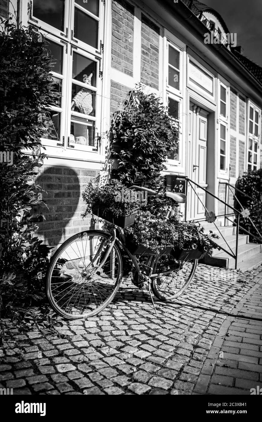 Vor einem alten Fachwerkhaus steht ein Fahrrad mit Blumen zur Dekoration gepflanzt Stockfoto