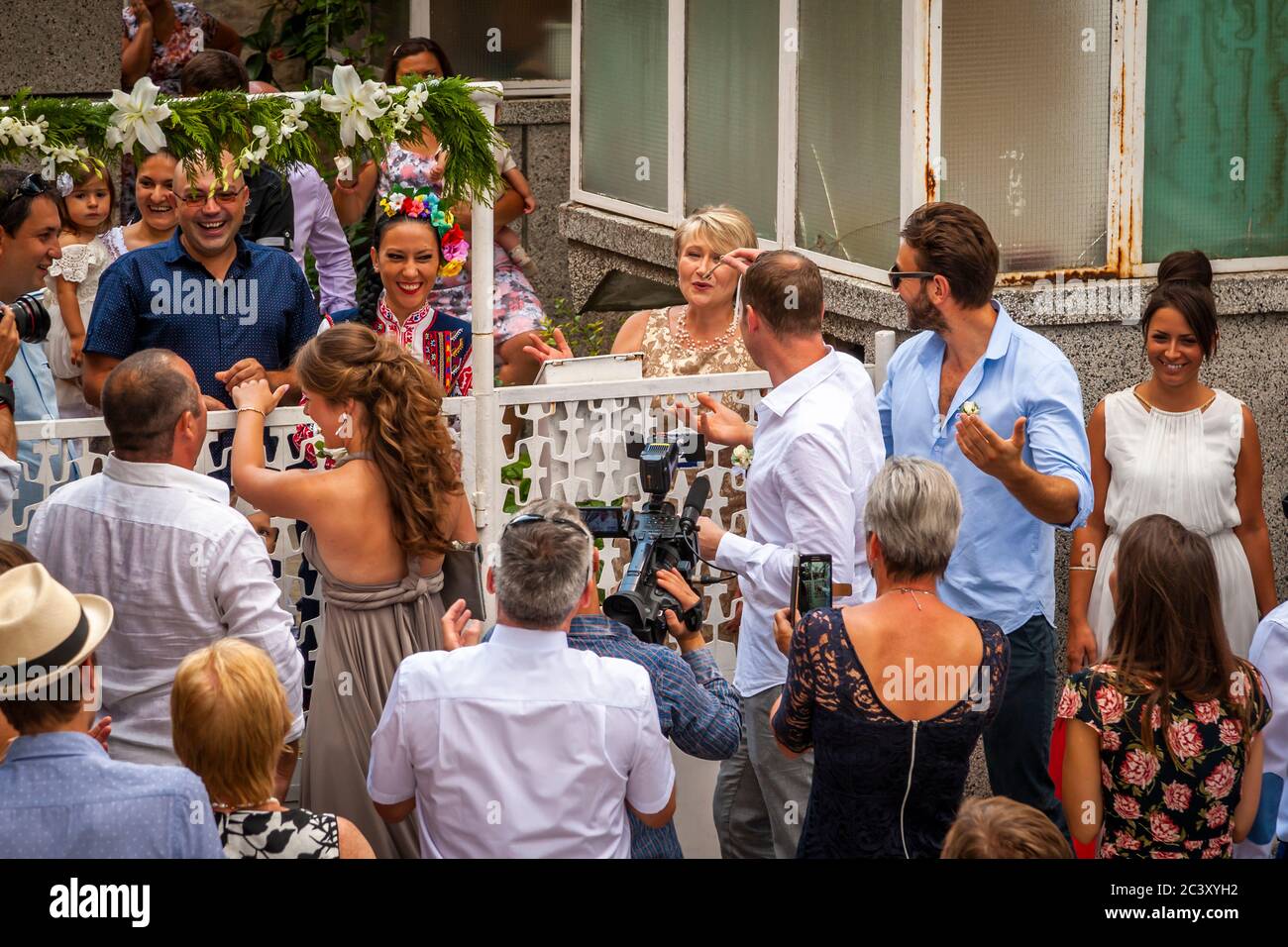 Bulgarische Hochzeit. Am Hochzeitstag wird die Braut im Haus ihrer Eltern aus der Hand des Bräutigams und seines Teams verteidigt Stockfoto