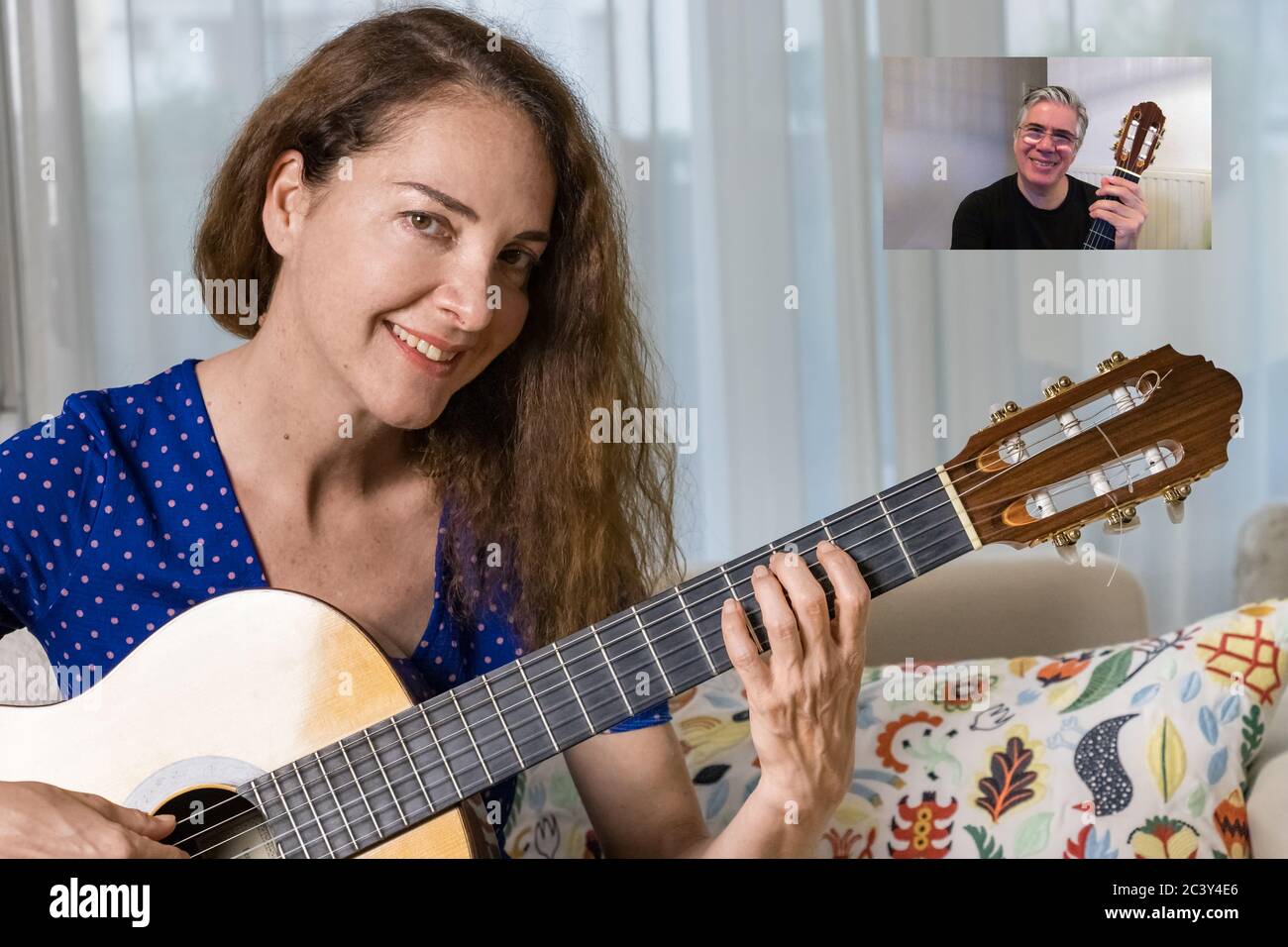 Weibliche Gitarrenlehrerin, die Online-Unterricht zu Hause für eine Erwachsene Schülerin gibt Stockfoto