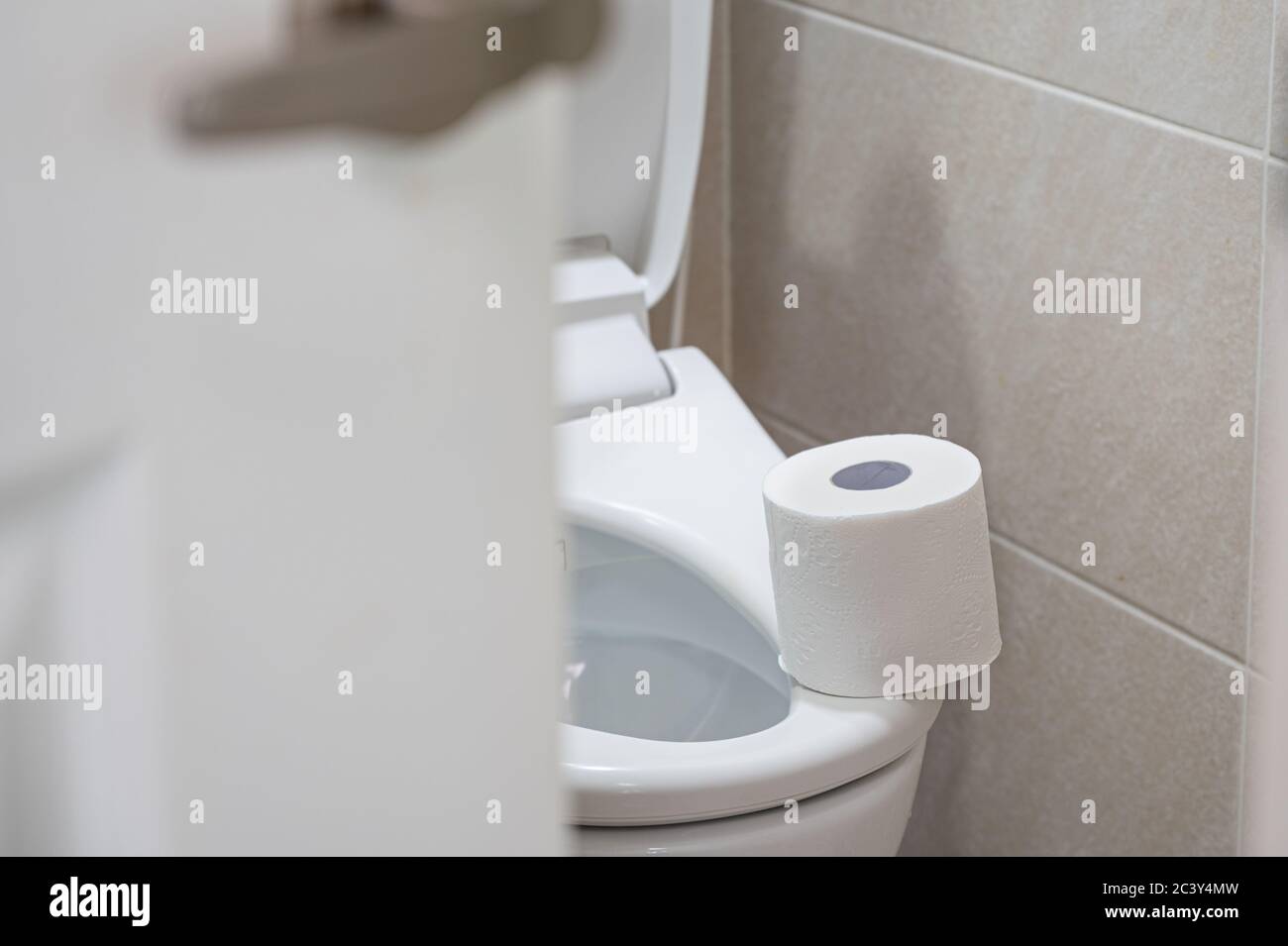 Rolle weißes Toilettenpapier in einem gefliesten Badezimmer. Stockfoto