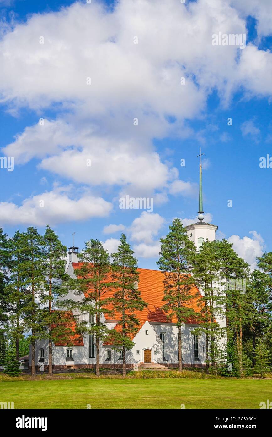 Schöne weiße lutherische Kirche von Pinien im ländlichen Finnland an einem sonnigen Sommertag umgeben Stockfoto