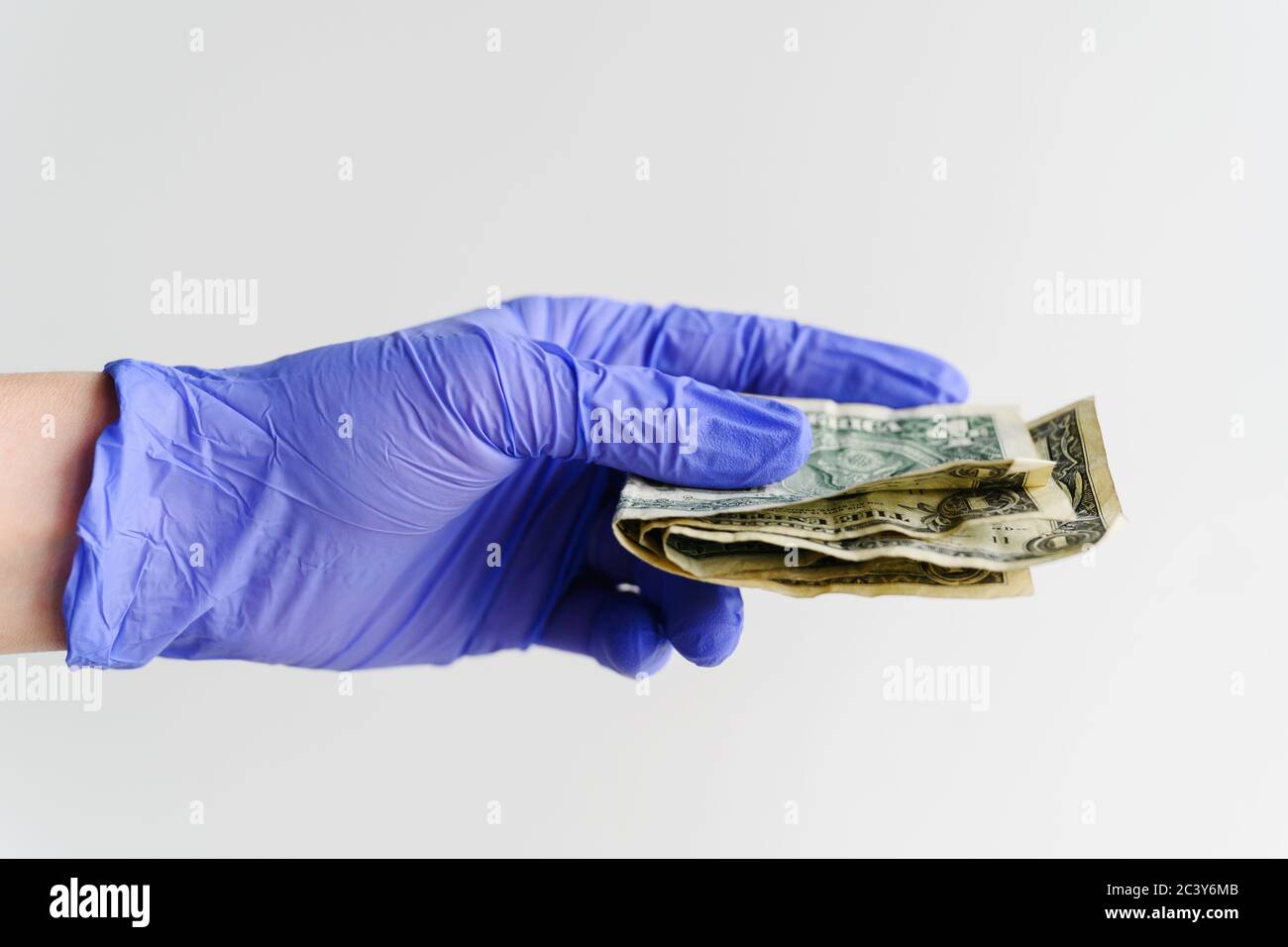 Studio Schuss der Hand in Latex-Handschuh hält gefalteten Dollar Rechnungen Stockfoto