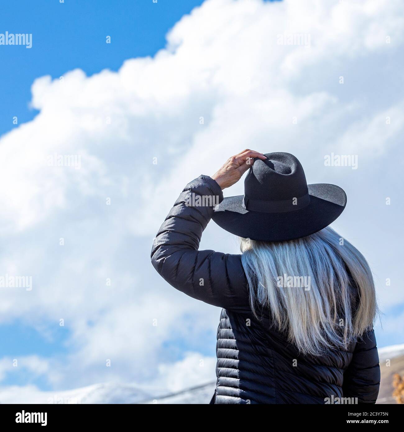 Porträt der älteren Frau trägt Hut gegen blauen Himmel und Wolken Stockfoto