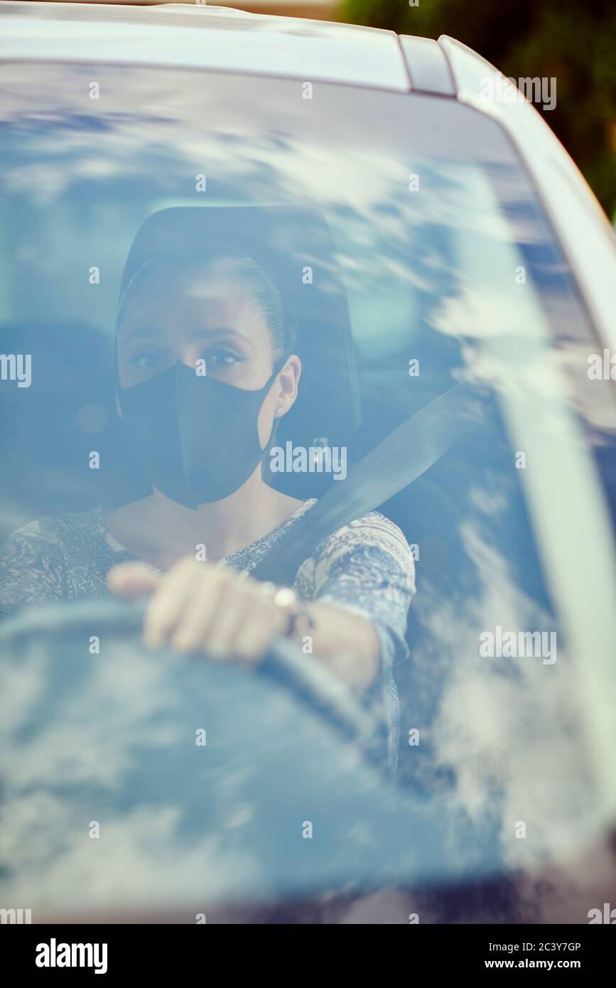 Frau mit Gesichtsmaske Auto fahren Stockfoto
