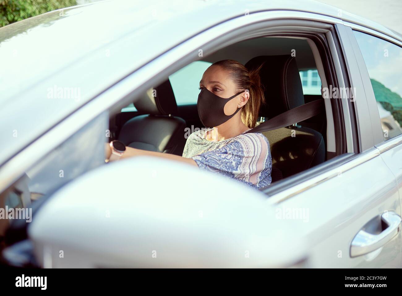 Frau mit Gesichtsmaske Auto fahren Stockfoto