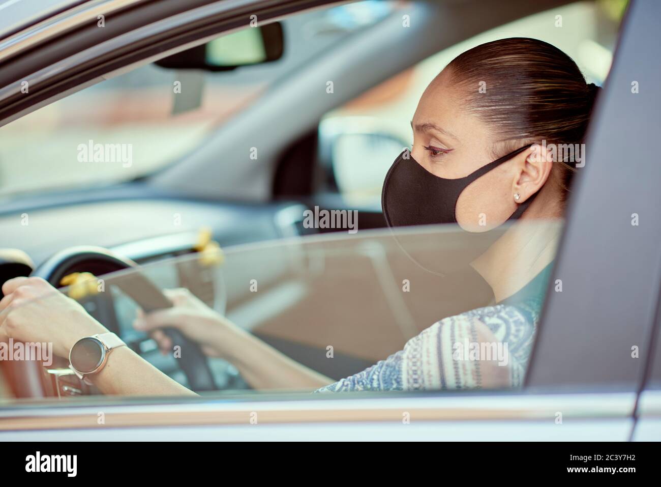 Frau mit Gesichtsmaske Auto fahren Stockfoto