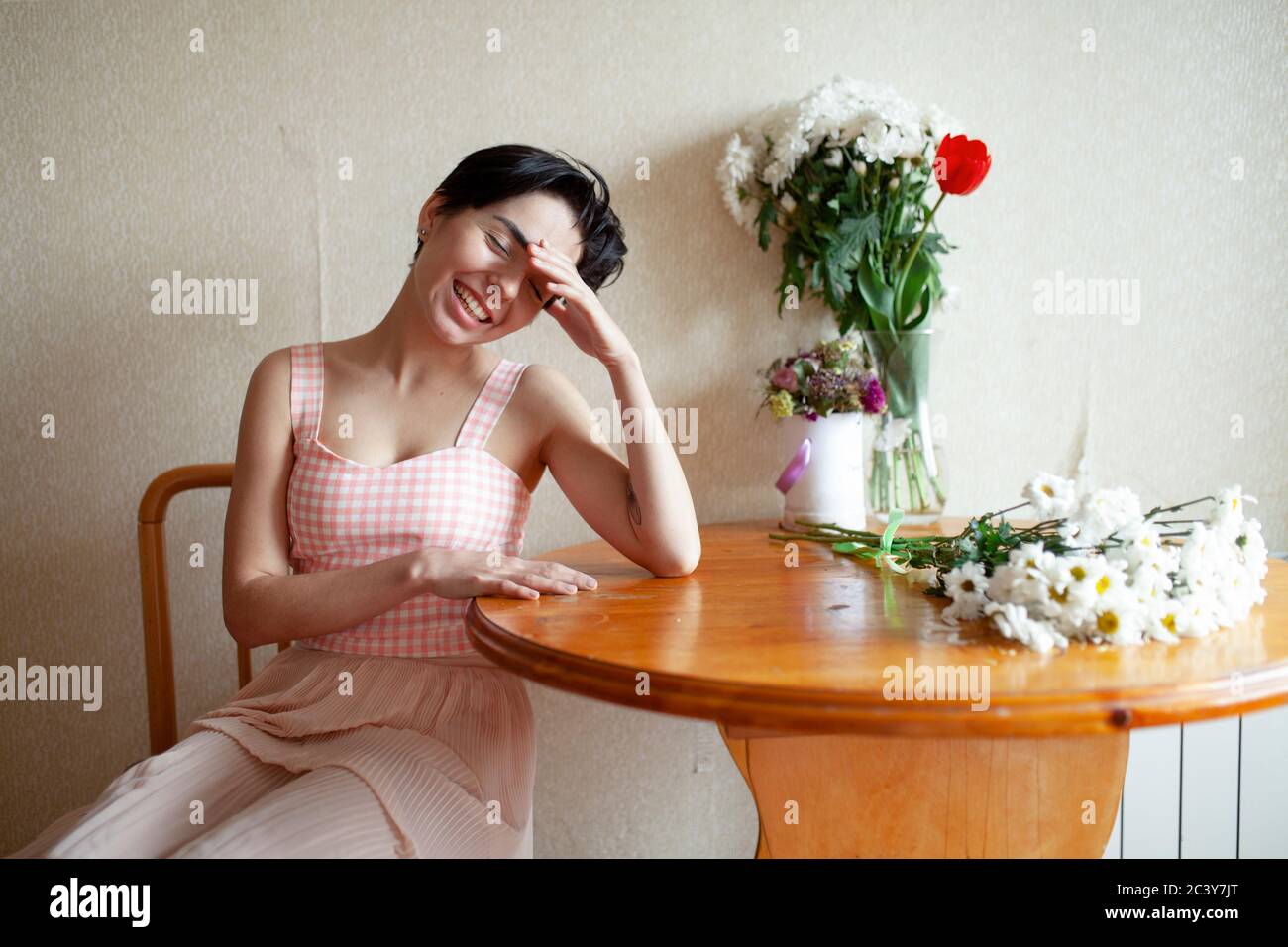 Junge Frau sitzt am Tisch mit Blumen Stockfoto