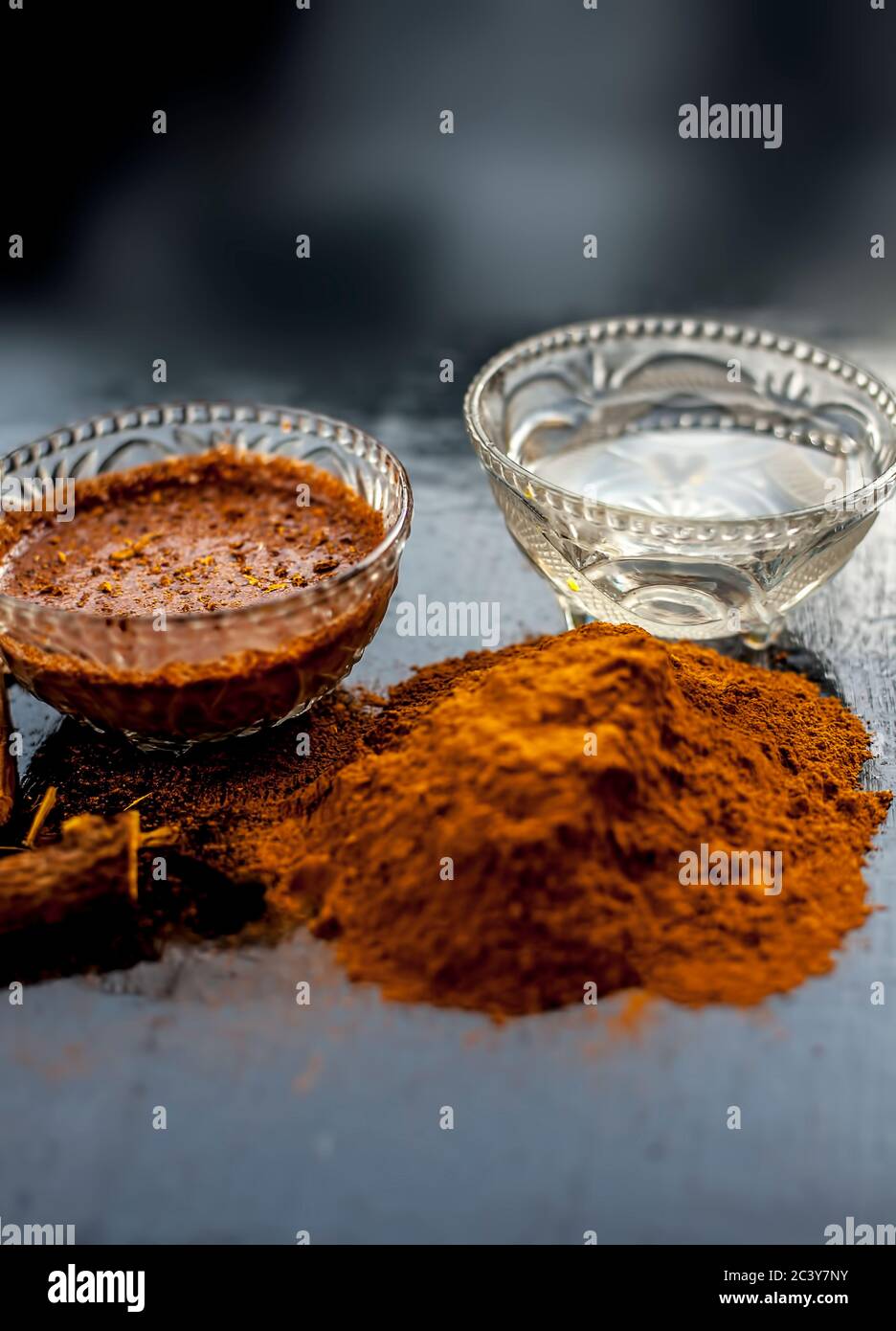 Nahaufnahme von frischen rohen Revand chini Wurzeln und seiner Paste in einer Glasschale zusammen mit etwas rohem Pulver auf einer schwarzen Holzoberfläche. Stockfoto