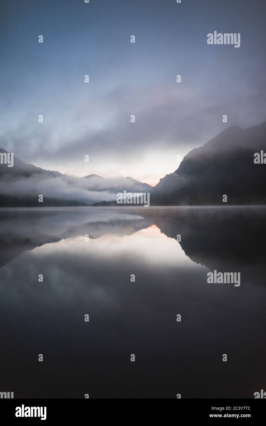 Österreich, Plansee, Plansee bei Sonnenaufgang im Nebel mit österreichischen Alpen Stockfoto