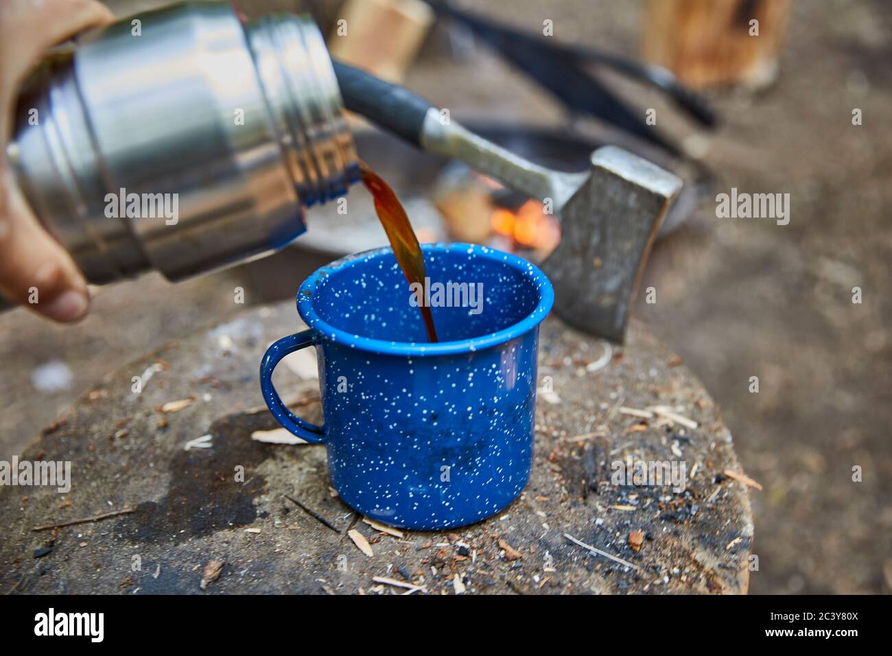 Mann, der Kaffee auf dem Campingplatz ausgießt Stockfoto