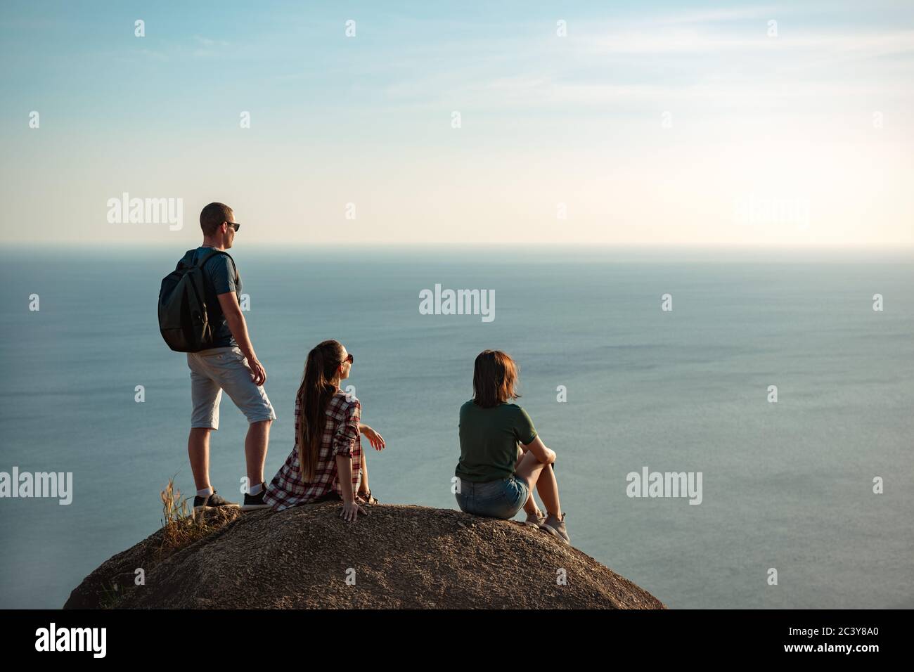 Drei junge Freunde genießen Sonnenuntergang Meer aus Bergperspektive Stockfoto