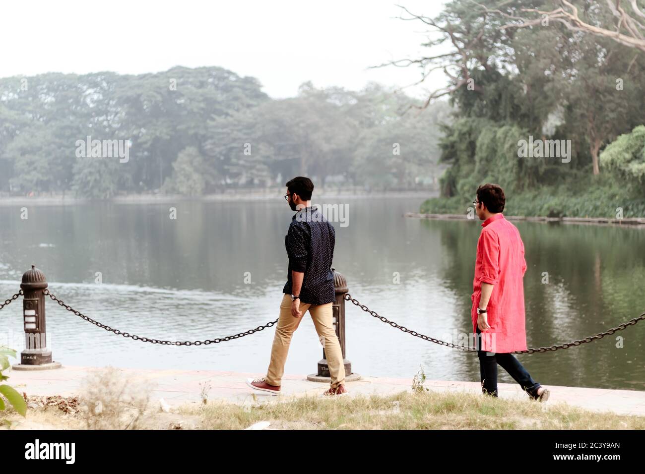 Zwei junge Leute, die am Sommerabend im Park zurück nach hinten wandern. Rabindra Sarobar (Dhakuria See) Süd-Kalkutta, Indischer Staat von West-Bengalen, Calc Stockfoto