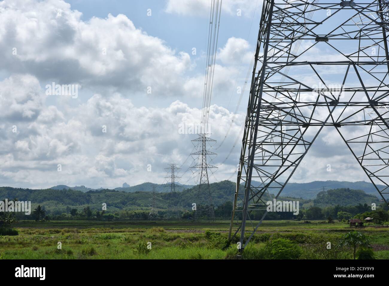 Hochspannungsturm, elektrische Post und elektrisches Kabel auf dem Feld in der Landschaft mit weiß bewölkt und blauen Himmel Hintergrund. Speicherplatz kopieren Stockfoto