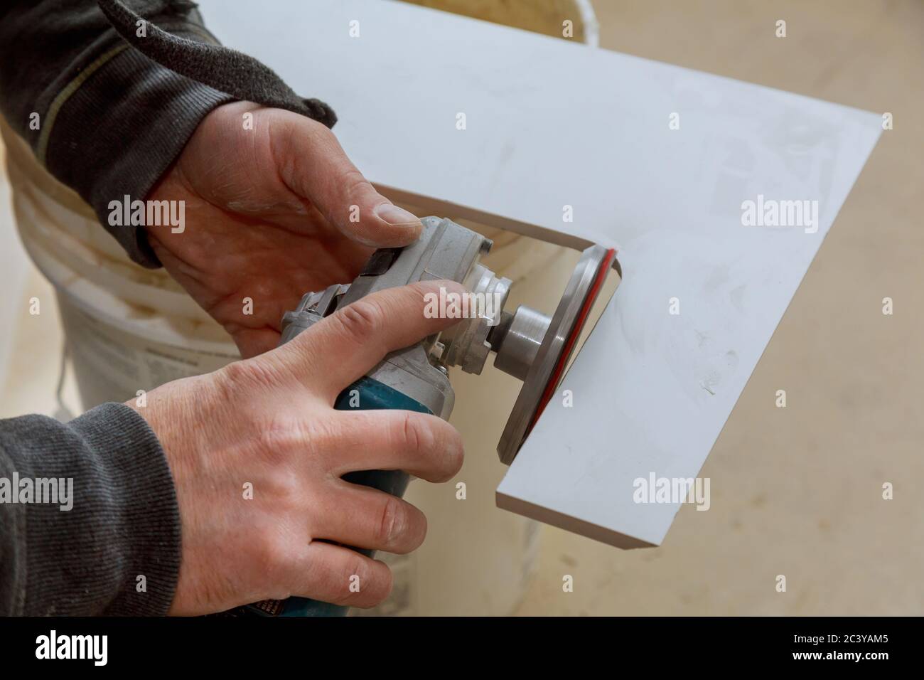 Arbeitnehmer im verwendet Schleifer für Schneiden von Fliesen Feinsteinzeug fliesen arbeiten Fräsen Stockfoto