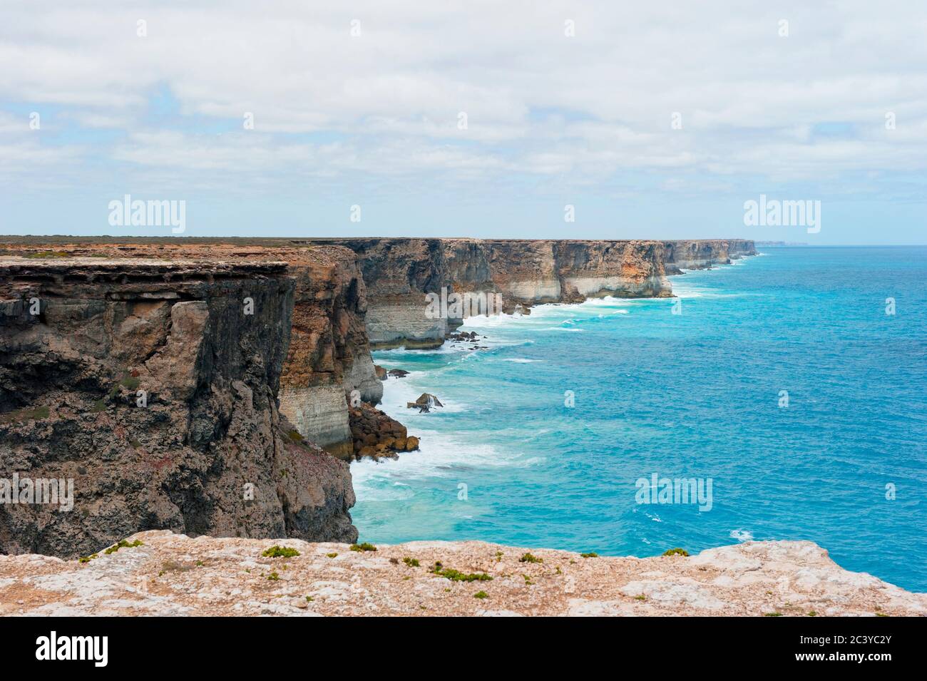 Malerische Landschaft von steilen Klippen entlang der Nullarbor-Ebene in Australien, mit türkisfarbenem Wasser des südlichen Ozeans, Horizont und wolkenbehallten Himmel als Bac Stockfoto