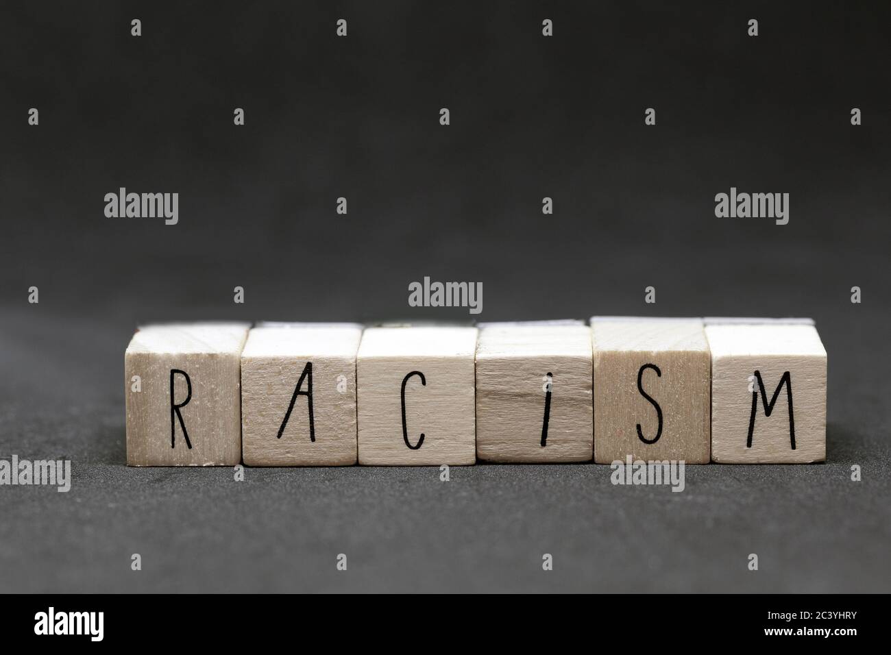 Holzwürfel mit dem Wort Rassismus auf dunklem Hintergrund, schwarz lebt Materie Konzept Stockfoto