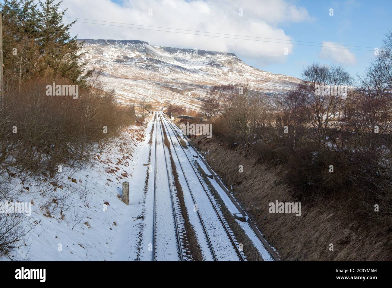 Verschneite Winteransicht der Settle und Carlisle Bahnlinie im Eden Valley mit Wildschwein fiel im Hintergrund Stockfoto