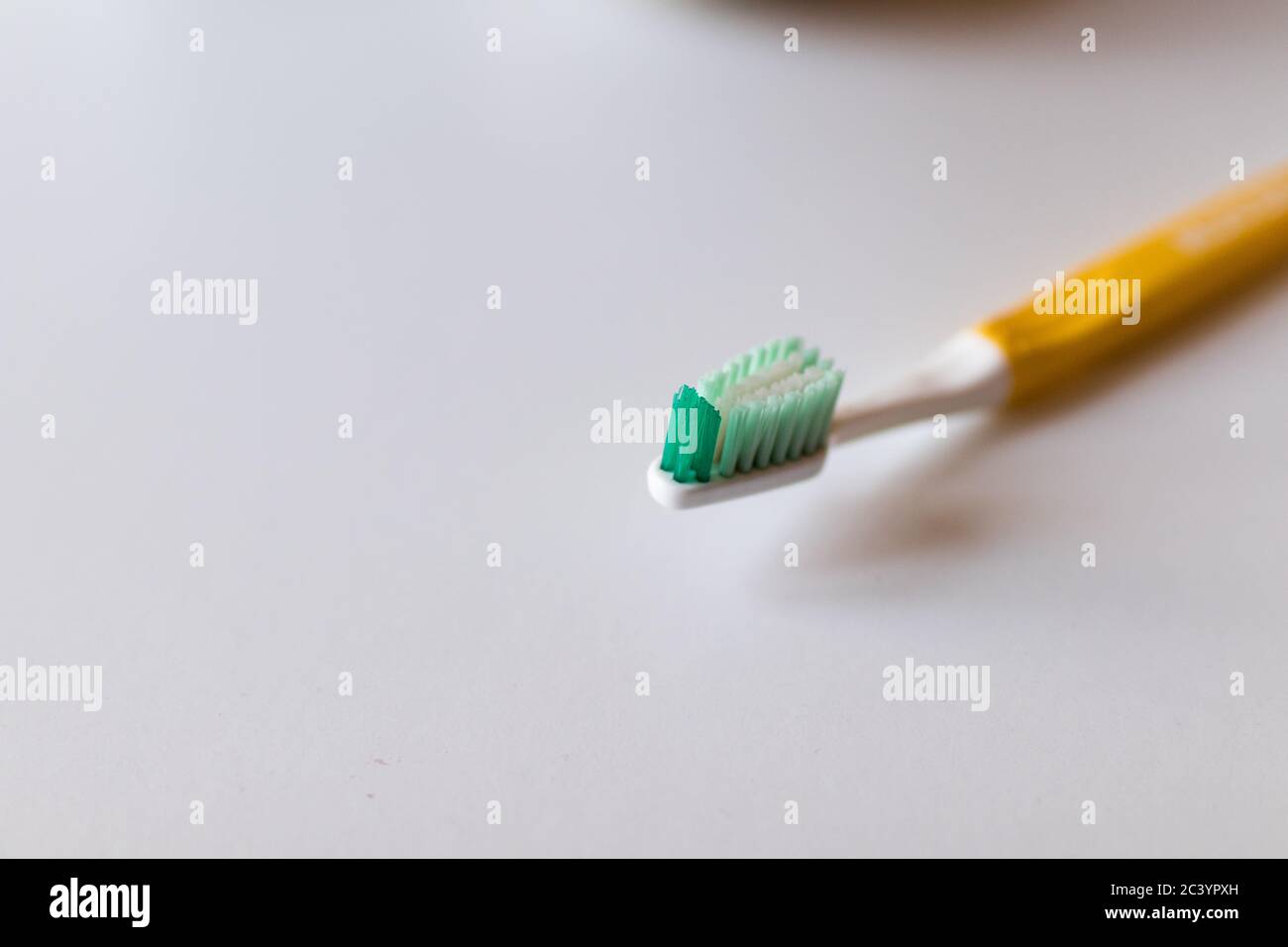 Zahnbürste mit weißen Grünborsten und gelbem Griff auf weißem Hintergrund Stockfoto