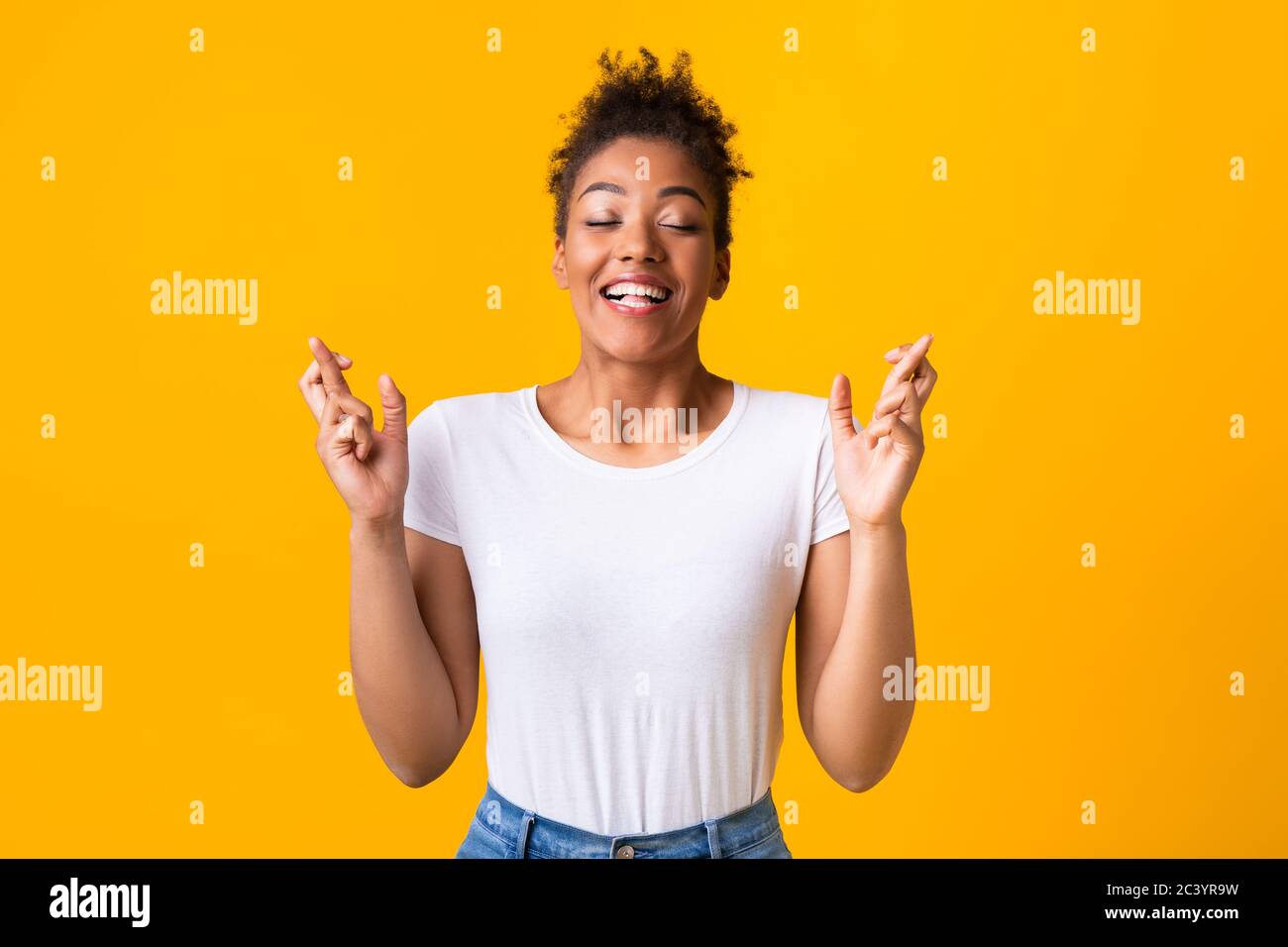 Hoffnungsvolles afroamerikanisches Mädchen, das ihre Finger kreuzt Stockfoto