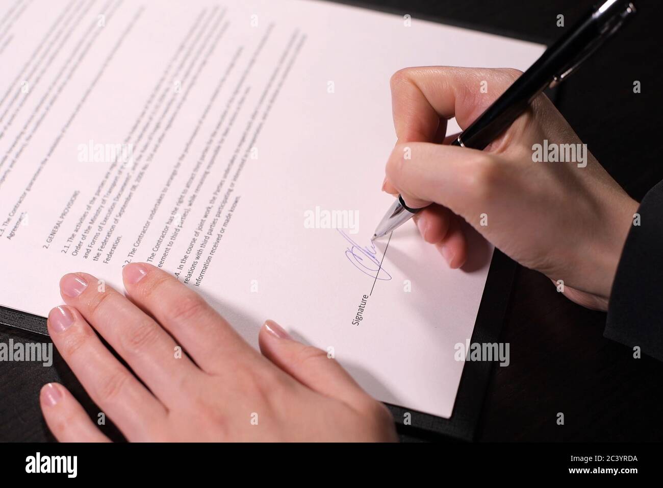 Frau setzt eine Unterschrift auf den Vertrag, Nahaufnahme Stockfoto