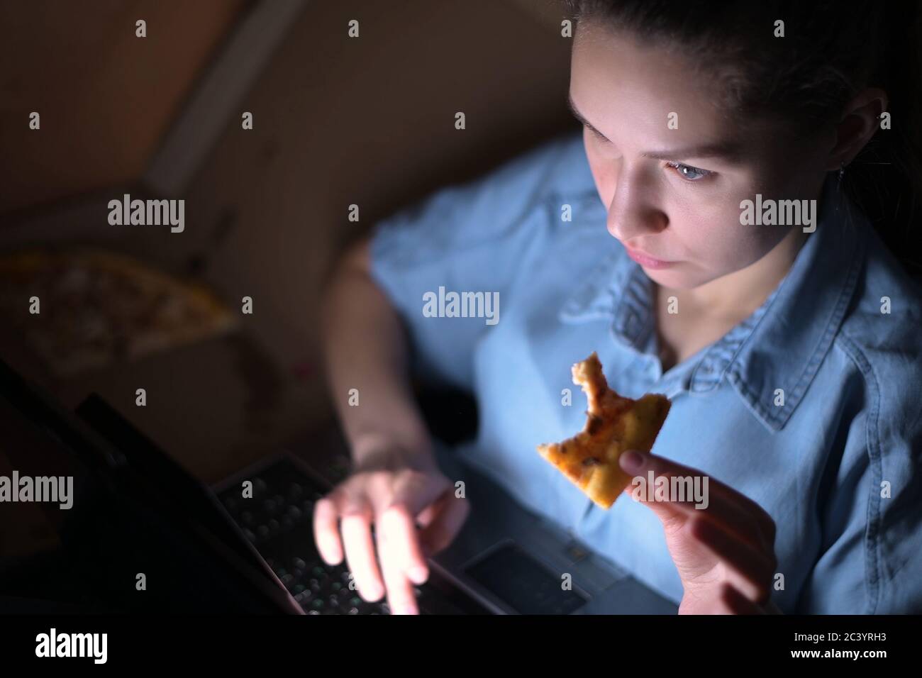 Mädchen isst Pizza und arbeitet an einem Laptop spät an Nacht Stockfoto