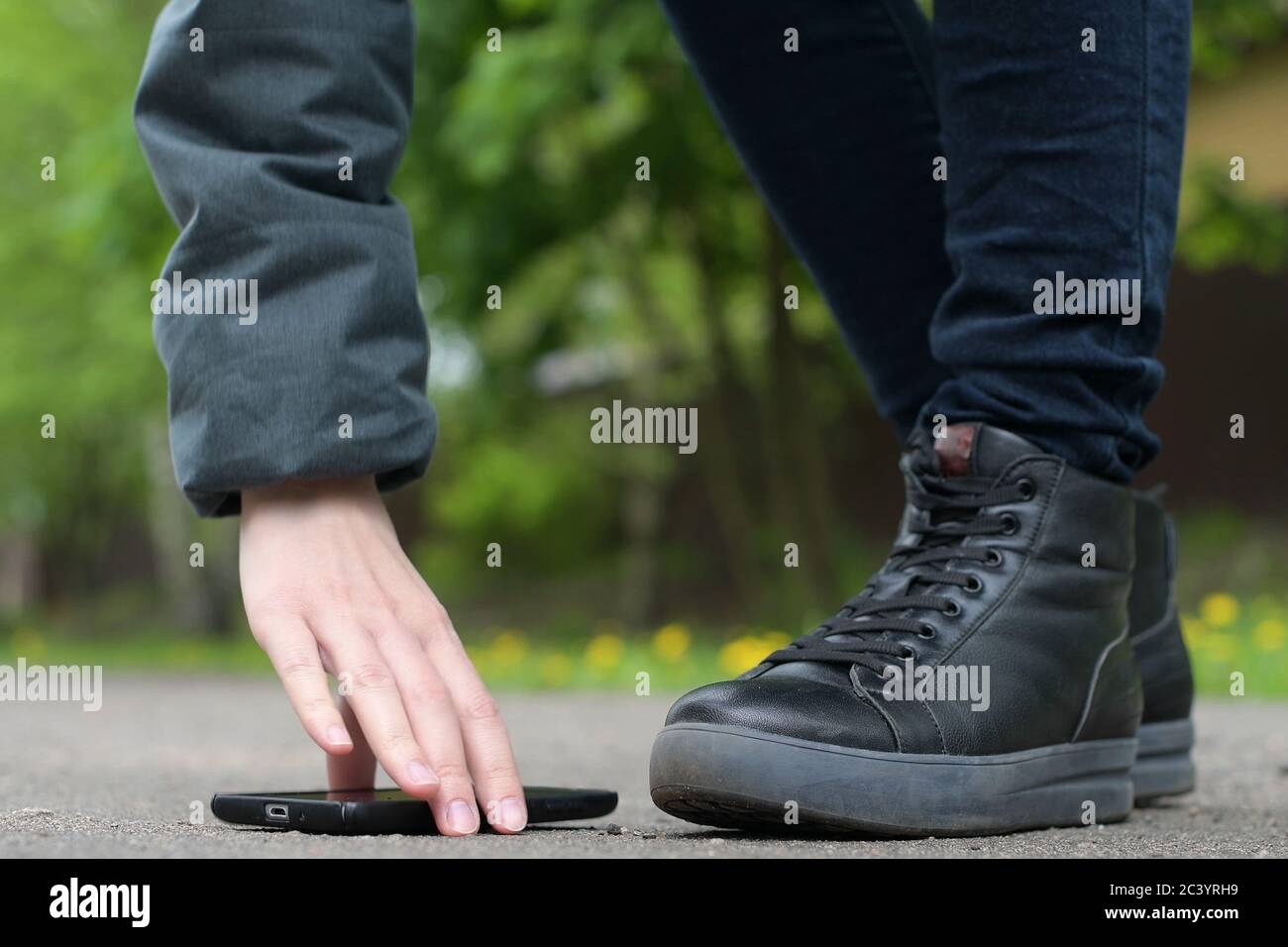 Das Mädchen findet ein Smartphone auf der Straße und wählt Es aus dem Asphalt Stockfoto