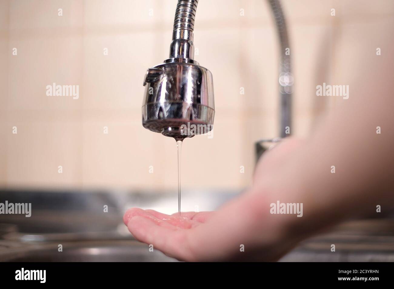Ein Mann öffnet einen Wasserhahn in der Küche, aber kein Wasser kommt. Überlappendes Wasser Stockfoto