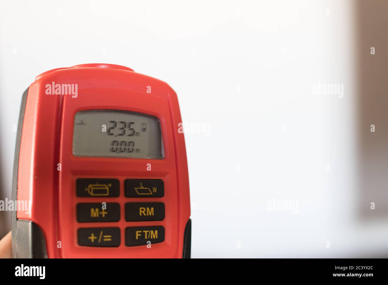 Ein orangefarbenes Lasermessgerät zeigte auf das Dach mit einer Länge von 2.35 Metern. Professionelle Werkzeuge für Architekten Stockfoto