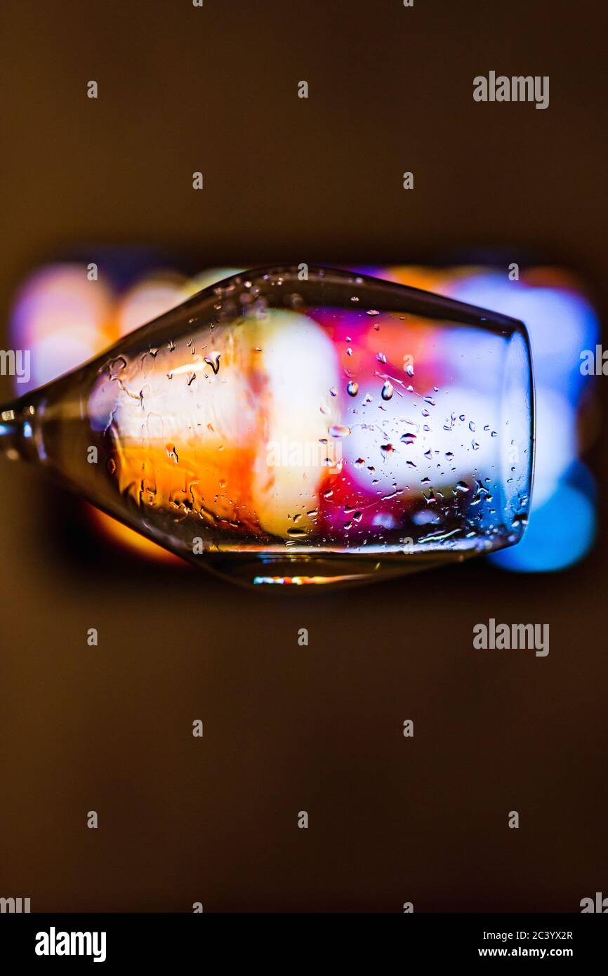 Eine Nahaufnahme eines Weinglases mit Tropfen Weißwein, Bokeh-Lichter im Hintergrund Stockfoto