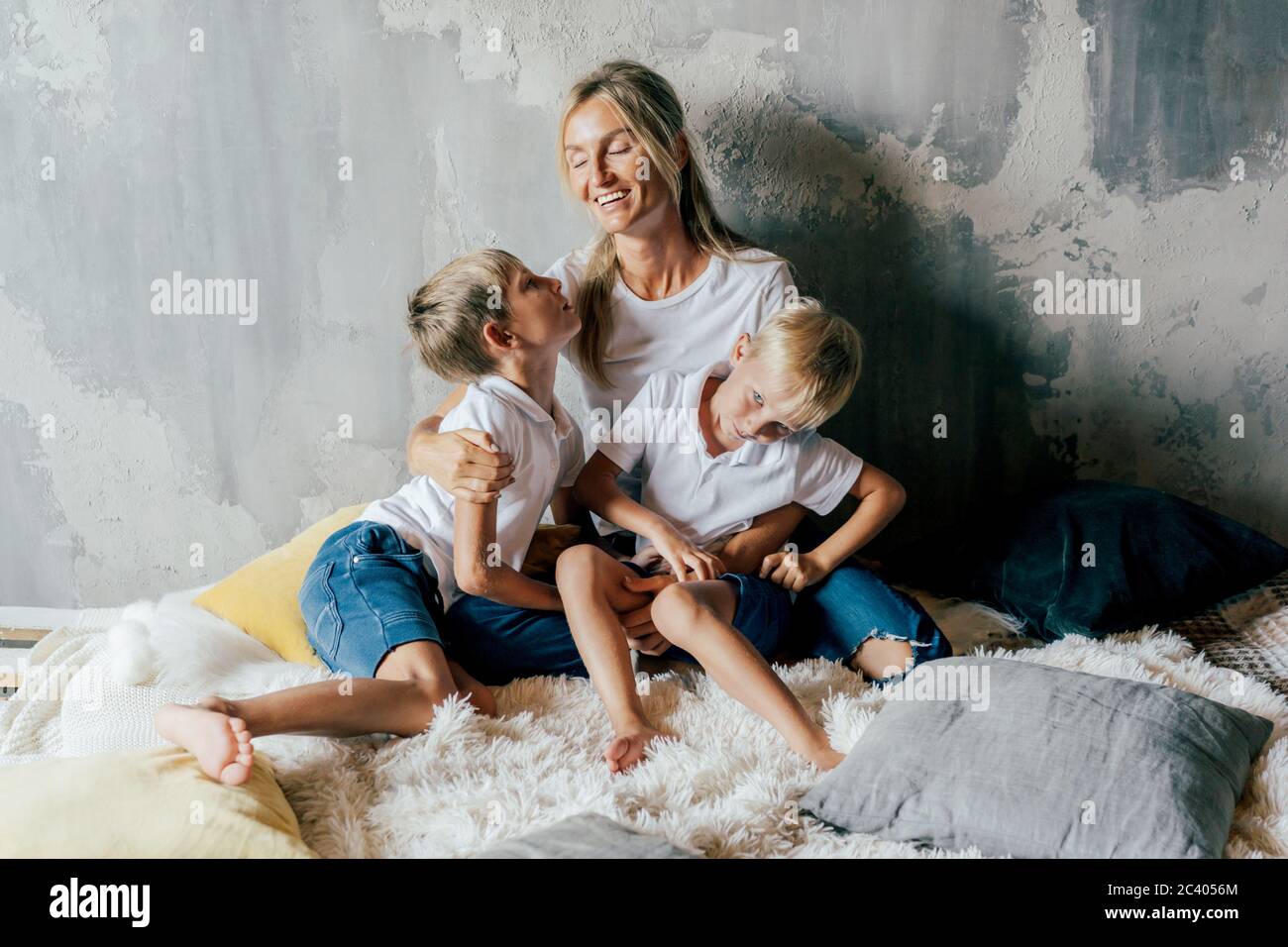 Schöne weiße junge Mutter umarmt ihre Söhne im Bett. Zeit mit der Familie. Lifestyle-Porträt. Stockfoto
