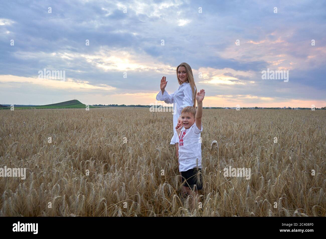 Glückliche Mutter und Sohn laufen durch ein Weizenfeld. Stockfoto