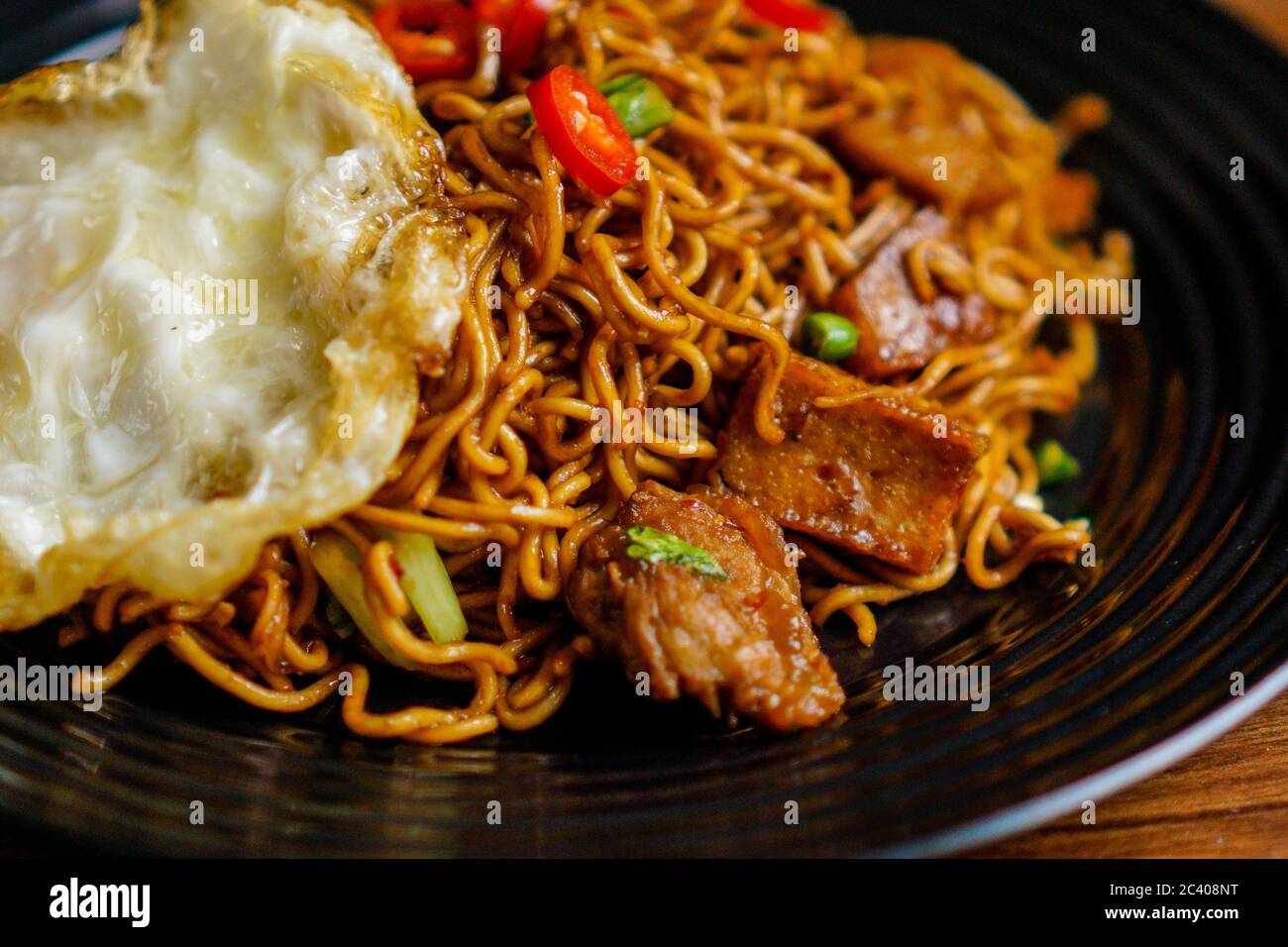 Dry Instant Noodle, malaysische maggi Goreng mamak oder würzige Dry Curry Instant Nudeln mit sonnigen Seite up Ei und Rindfleisch. Stockfoto