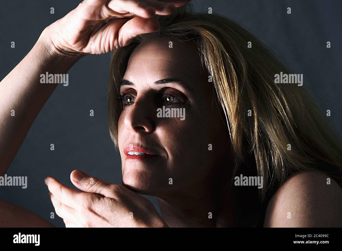 Erwachsene Frau, die mit ihren Händen in der Nähe ihres Gesichts herumspielt Stockfoto