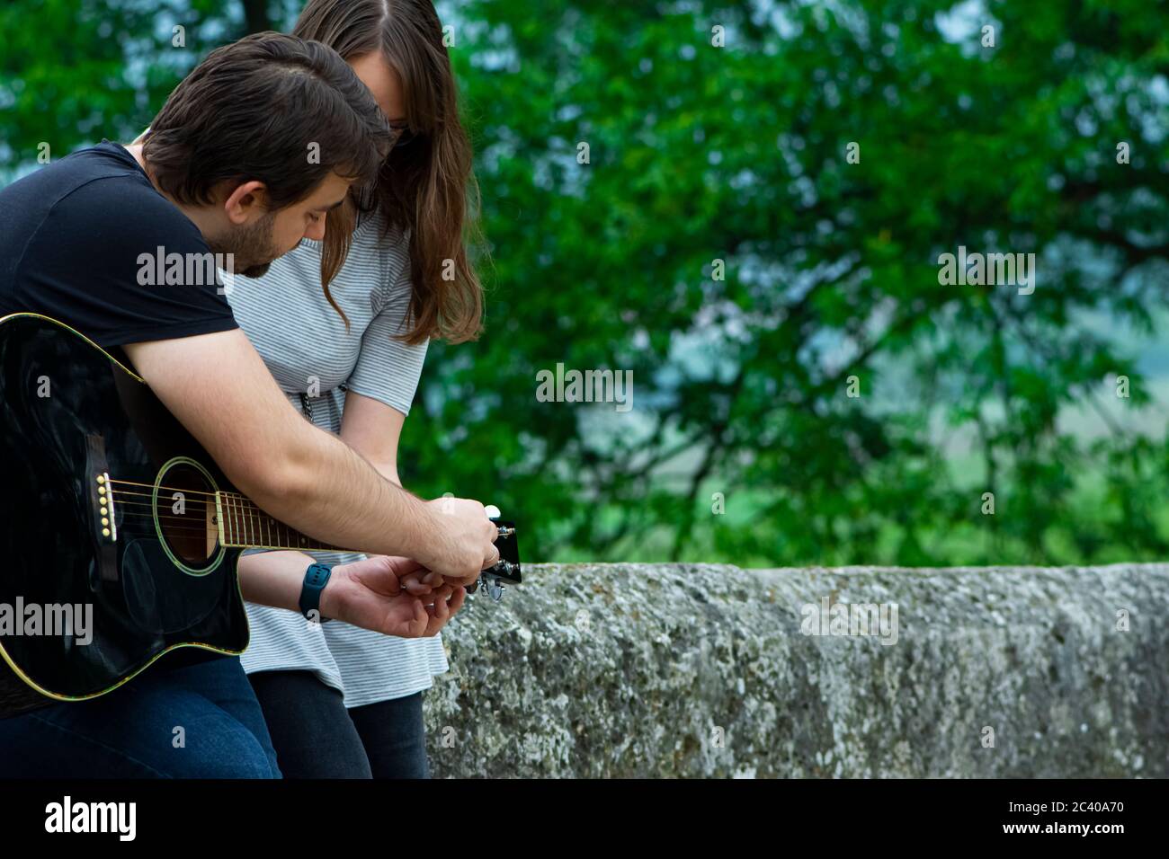 Bruder lehrt Schwester Gitarre in der Natur zu spielen Stockfoto
