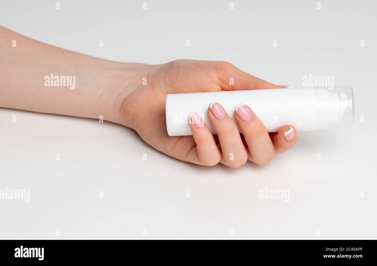 Weibliche Hand hält kosmetische Flasche auf weiß Stockfoto