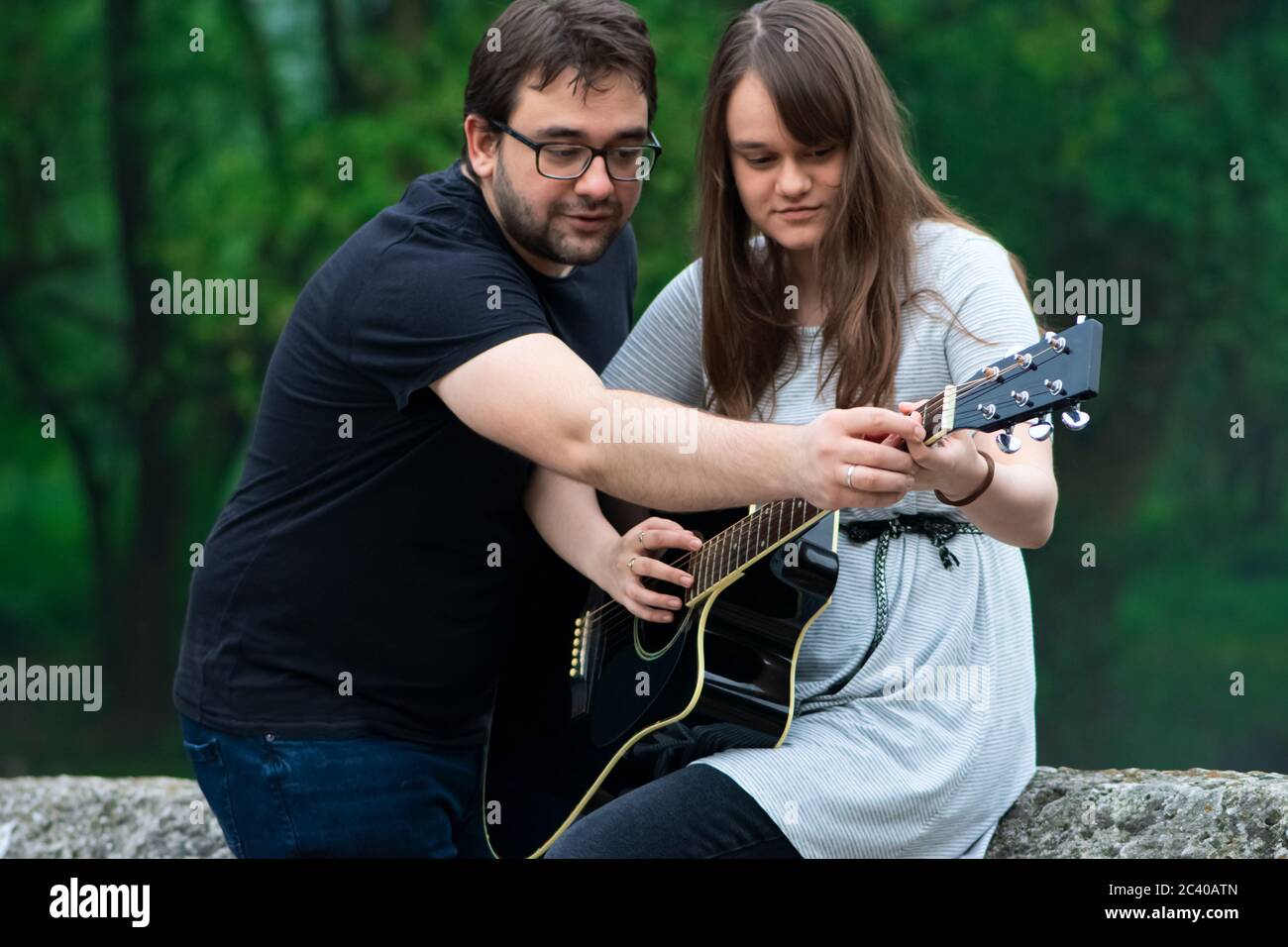 Bruder lehrt Schwester Gitarre in der Natur zu spielen Stockfoto