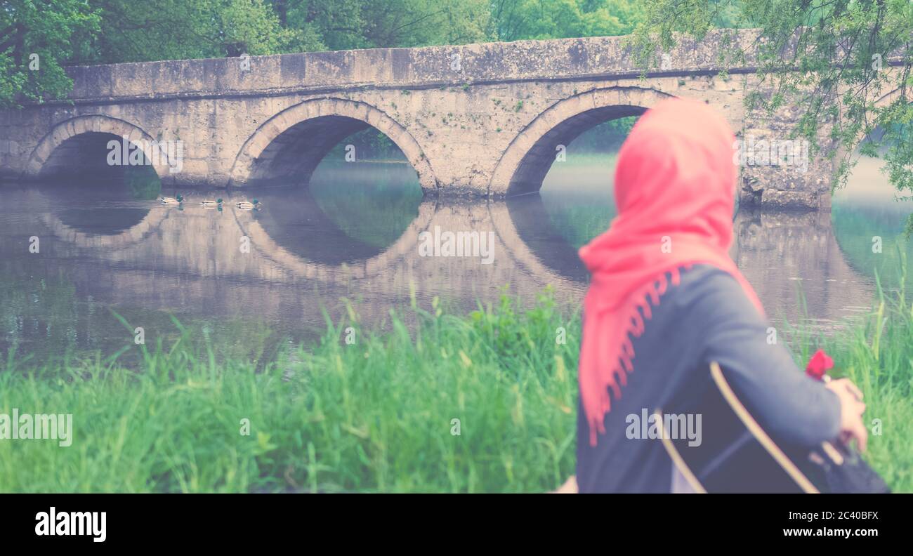 Muslim Mädchen Gitarre spielen und Blick auf die Brücke Stockfoto