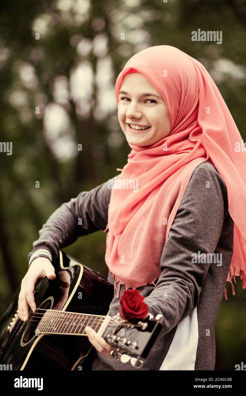 Portreit von glücklichen muslimischen Mädchen versuchen, Gitarre zu spielen Stockfoto