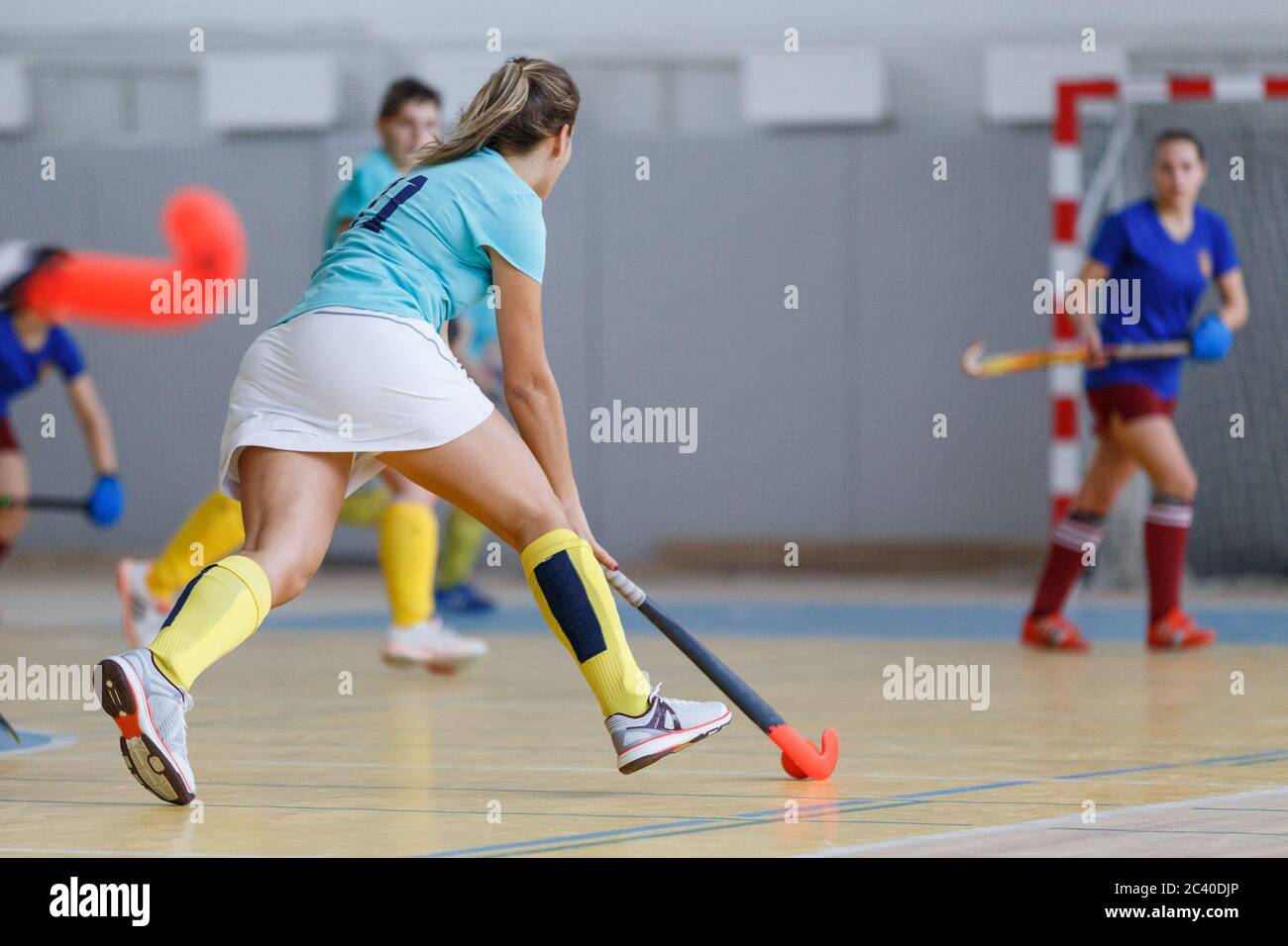 Junge weibliche Indoor-Hockey-Spieler mit dem Ball in Angriff. Stockfoto