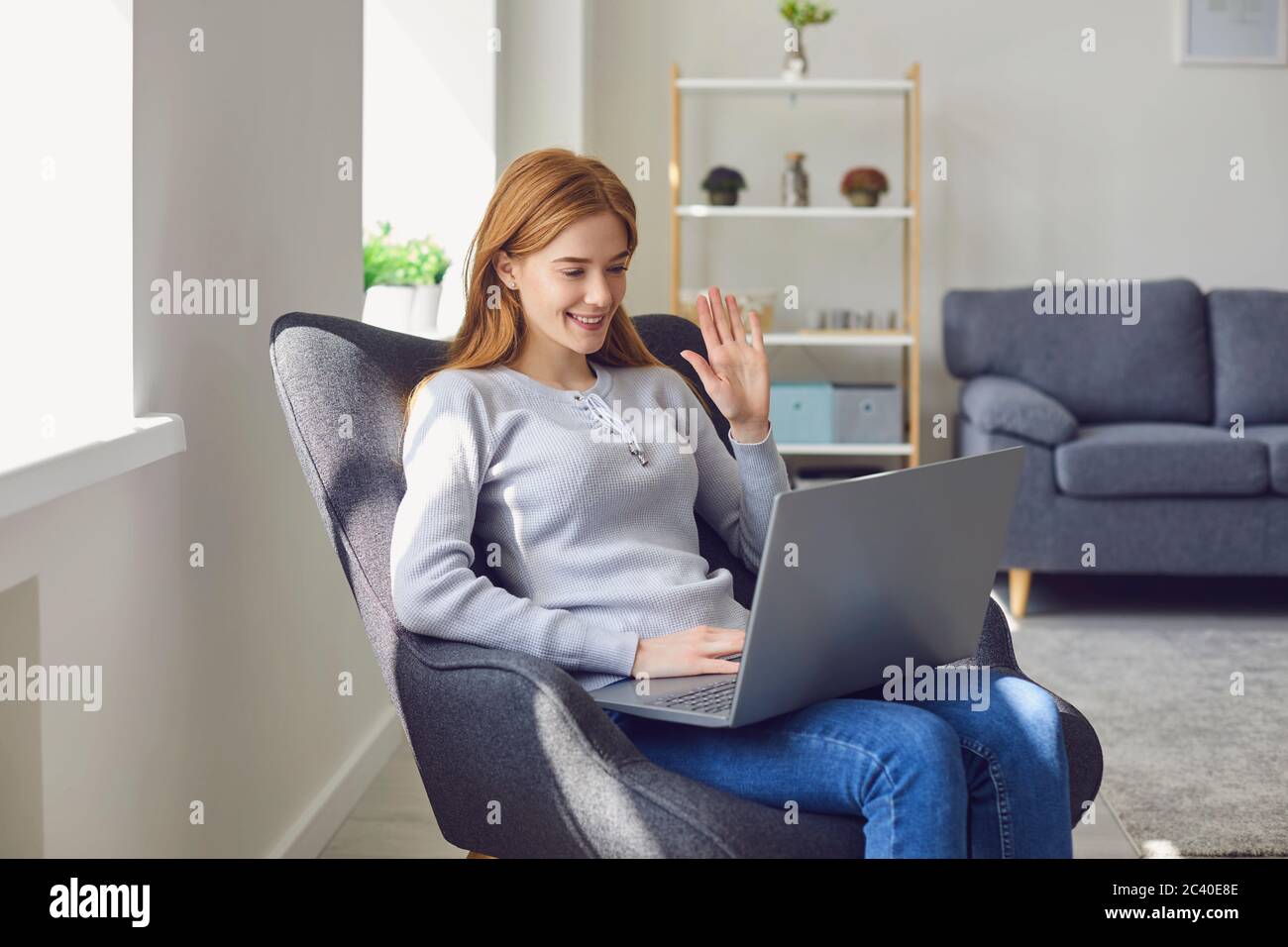 Mädchen zu Hause online. Entzückte Frau mit Laptop in modernen Wohnzimmer. Stockfoto